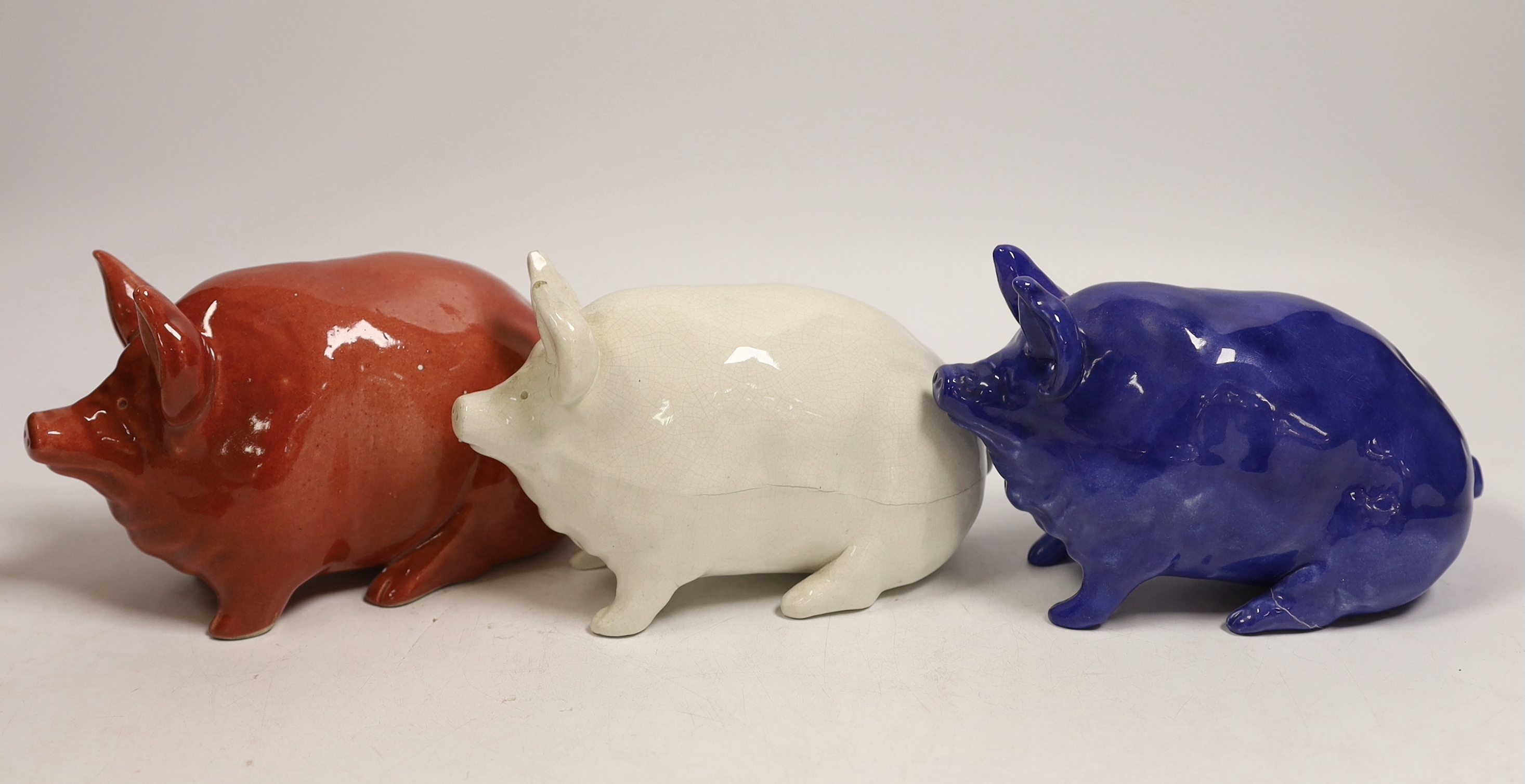 Three Wemyss ware pigs in cream, blue and pink glazes, 15cm